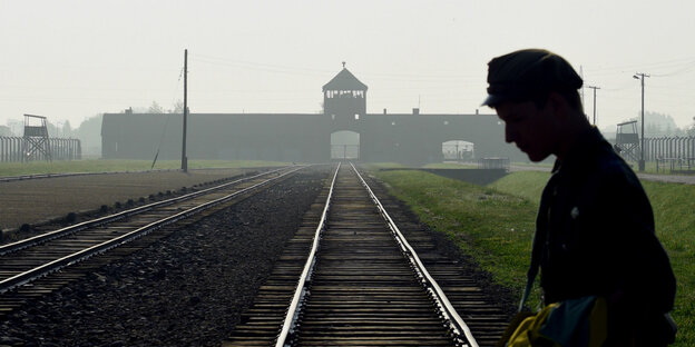Silhouette eines Mannes mit Mütze vor der Rampe von Auschwitz Silhouette eines Mannes mit Mütze vor der Rampe von Auschwitz