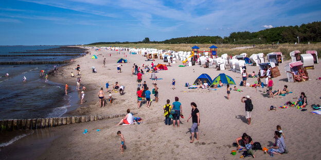 Menschen stehen und sitzen am Strand