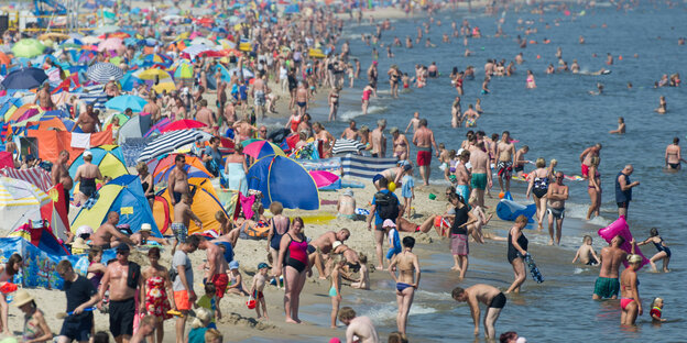 Ganz viele Menschen stehen an einem Strand Ganz viele Menschen stehen an einem Strand