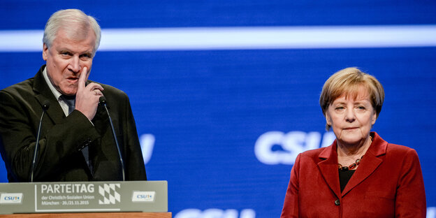 Seehofer steht am Rednerpult und kratzt sich im Gesicht, Merkel steht daneben Seehofer steht am Rednerpult und kratzt sich im Gesicht, Merkel steht daneben