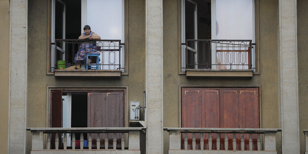 Eine Frau schaut vom Balkon Eine Frau schaut vom Balkon