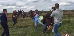 Kamerafrau inmitten rennender Flüchtlinge, einem von ihnen stellt sie ein Bein
