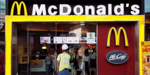 Ein Mann mit einem Bauarbeiter-Helm geht in eine Filiale von McDonalds Ein Mann mit einem Bauarbeiter-Helm geht in eine Filiale von McDonalds