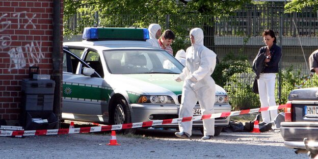 Abgespertter NSU-Mord-Tatort in Heilbronn mit dem Polizeiauto, Beamte in Schutzanzügen drumherum Abgespertter NSU-Mord-Tatort in Heilbronn mit dem Polizeiauto, Beamte in Schutzanzügen drumherum