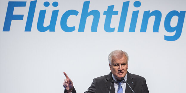 Horst Seehofer zeigt auf den Schriftzug "Flüchtling"