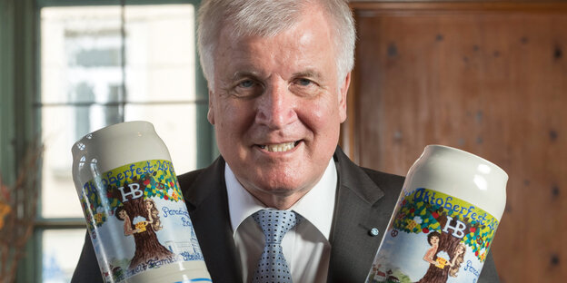 Horst Seehofer hält grimmig lächelnd zwei Bierkrüge in den Händen Horst Seehofer hält grimmig lächelnd zwei Bierkrüge in den Händen