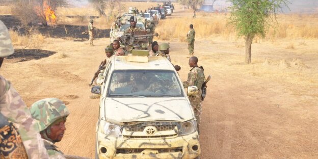 Ein langer Autokonvoi eines Militärs in einer wüstenähnlichen Gegend Ein langer Autokonvoi eines Militärs in einer wüstenähnlichen Gegend
