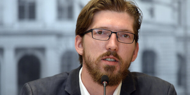 Ein Mann mit Brille spricht in ein Mikrofon Ein Mann mit Brille spricht in ein Mikrofon