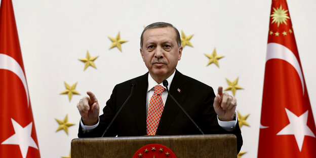 Recep Tayyip Erdoğan steht zwischen zwei türkischen Fahnen Recep Tayyip Erdoğan steht zwischen zwei türkischen Fahnen
