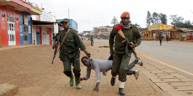 Kongolesische Soldaten schleifen einen Demonstranten über eine Straße Kongolesische Soldaten schleifen einen Demonstranten über eine Straße