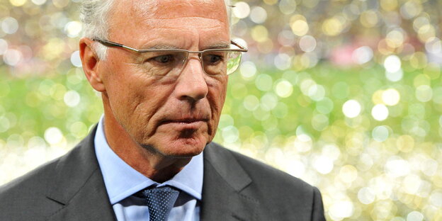 Beckenbauer guckt ernst, hinter im ist unscharf glitzerner Regen zu erkennen Beckenbauer guckt ernst, hinter im ist unscharf glitzerner Regen zu erkennen
