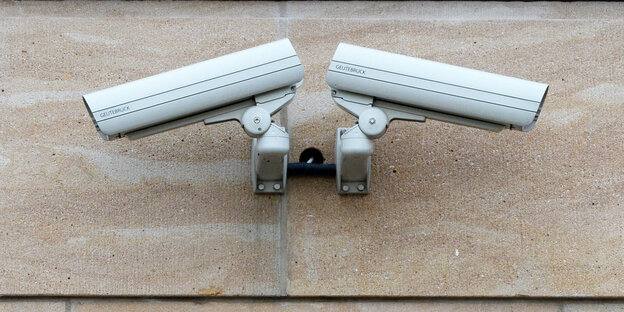 Zwei Videokameras hängen an einer Wand Zwei Videokameras hängen an einer Wand