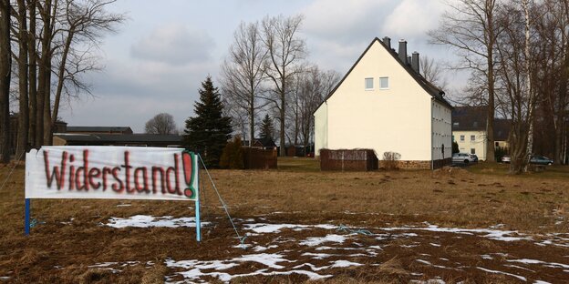 Ein Banner auf einer Wiese. Auf ihm steht „Widerstand“. Dahinter befindet sich ein Haus. Ein Banner auf einer Wiese. Auf ihm steht „Widerstand“. Dahinter befindet sich ein Haus.