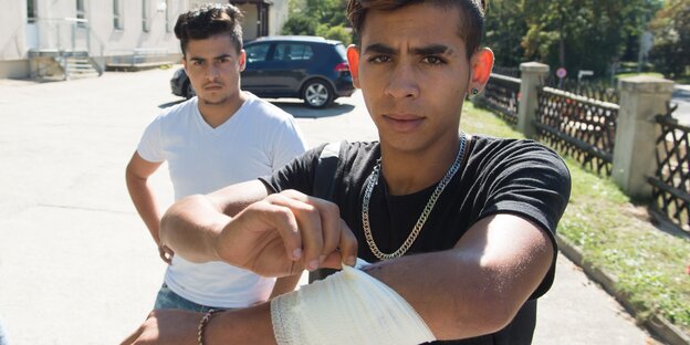Ein junger Mann zeigt eine Mullbinde an seinem Arm Ein junger Mann zeigt eine Mullbinde an seinem Arm