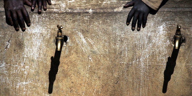 Eine Hand hält sich am becken neben zwei Wasserhähnen fest Eine Hand hält sich am becken neben zwei Wasserhähnen fest