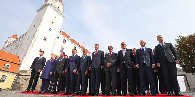 viele Männer und wenige Frauen stehen für ein Foto auf einem roten Teppich vor einer Burg viele Männer und wenige Frauen stehen für ein Foto auf einem roten Teppich vor einer Burg