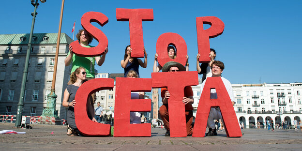 Menschen, die Buchstaben hochhalten, die die Wörter "Stop Ceta" ergeben Menschen, die Buchstaben hochhalten, die die Wörter "Stop Ceta" ergeben