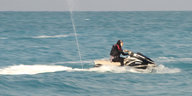 Eine Burkini-Trägerin steuert einen Jetski auf dem Wasser