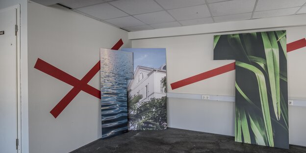 Ein Raum mit großformatigen Fotos und roten Streifen an der Wand Ein Raum mit großformatigen Fotos und roten Streifen an der Wand
