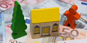 Kleine Holzfiguren zeigen ein grünes Bäumchen, ein gelbes Häuschen und ein rotes Menschlein