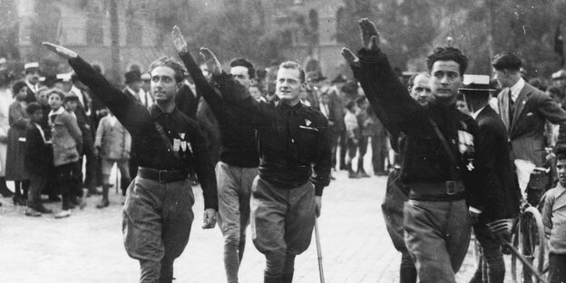 Männer in schwarzen Uniformen heben die rechte Hand zum fschistischen Gruß Männer in schwarzen Uniformen heben die rechte Hand zum fschistischen Gruß