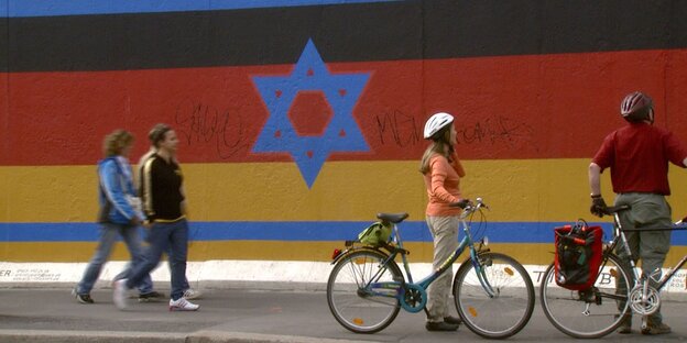 Eine Collage am Rest der Berliner Mauer: Die deutsche und die israelische Flagge liegen übereinander Eine Collage am Rest der Berliner Mauer: Die deutsche und die israelische Flagge liegen übereinander