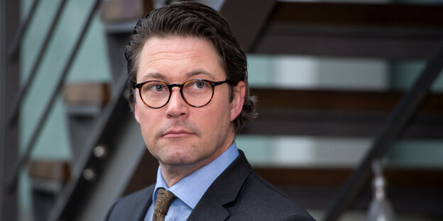 Ein Mann mit dunklen, zurückgegelten Haaren und Brille Ein Mann mit dunklen, zurückgegelten Haaren und Brille