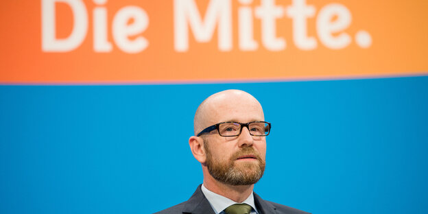 Peter Tauber steht vor einem Plakat, auf dem "die Mitte" steht