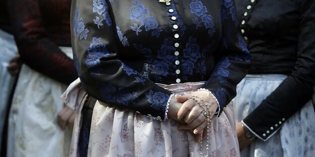 Eine Frau in bayerischer Tracht faltet die Hände vor dem Bauch Eine Frau in bayerischer Tracht faltet die Hände vor dem Bauch