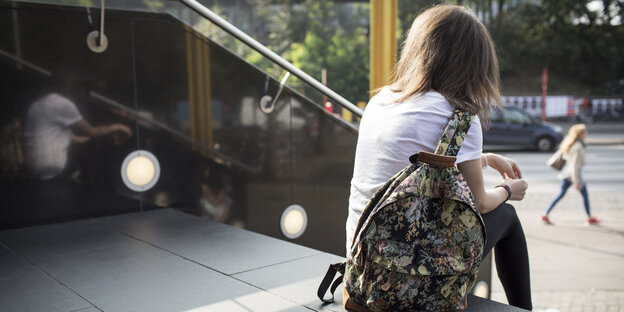 Eine Frau sitzt mit einer Tasche auf einer Treppe Eine Frau sitzt mit einer Tasche auf einer Treppe