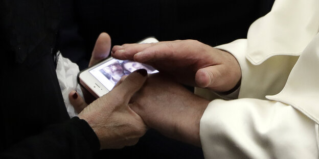 Hände legen sich schützend über ein Smartphone Hände legen sich schützend über ein Smartphone