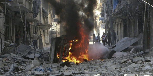 ein brennendes Fahrzeug in einer völlig zerstörten Straße in Aleppo ein brennendes Fahrzeug in einer völlig zerstörten Straße in Aleppo