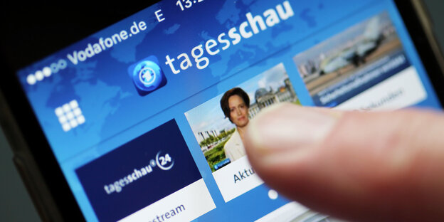 Ein Finger zeigt auf ein Smartphone auf der die Tagesschau-App läuft Ein Finger zeigt auf ein Smartphone auf der die Tagesschau-App läuft