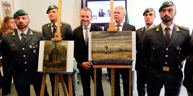 Die Mitarbeiter der Guardia di Finanza stehen neben den wiedergefundenen Van-Gogh-Gemälden Die Mitarbeiter der Guardia di Finanza stehen neben den wiedergefundenen Van-Gogh-Gemälden