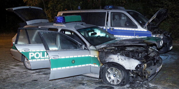 zwei ausgebrannte Polizeifahrzeuge