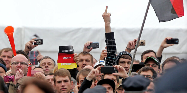 Ein Pegida-Demonstrant in der Menge zeigt den Stinkefinger Ein Pegida-Demonstrant in der Menge zeigt den Stinkefinger
