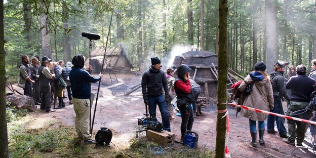 Eine Filmcrew steht im Wald vor Kohlenmeilern Eine Filmcrew steht im Wald vor Kohlenmeilern