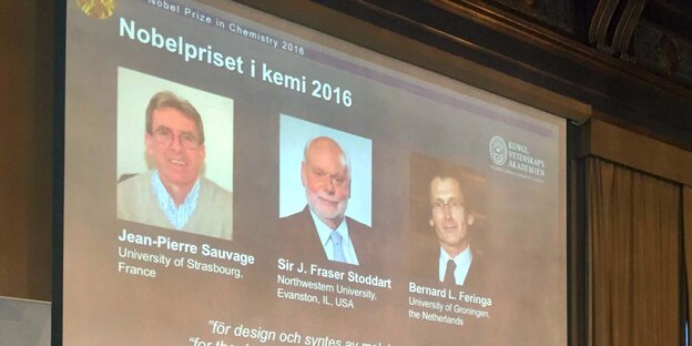 Die drei Chemie-Nobelpreisgewinner 2016 sind auf der Leinwand über der Jury zu sehen Die drei Chemie-Nobelpreisgewinner 2016 sind auf der Leinwand über der Jury zu sehen