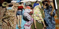 Fünf Jugendlche schlafen auf Isomatten unter bunten Decken