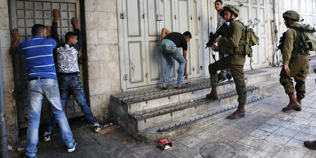Israelische Soldaten halten palästinensische Jugendliche mit vorgehaltenem Gewehr in Schach Israelische Soldaten halten palästinensische Jugendliche mit vorgehaltenem Gewehr in Schach