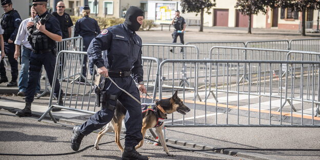 Vor einer Absperrung sind Polizisten zu sehen, einer mit einem Polizeihund Vor einer Absperrung sind Polizisten zu sehen, einer mit einem Polizeihund