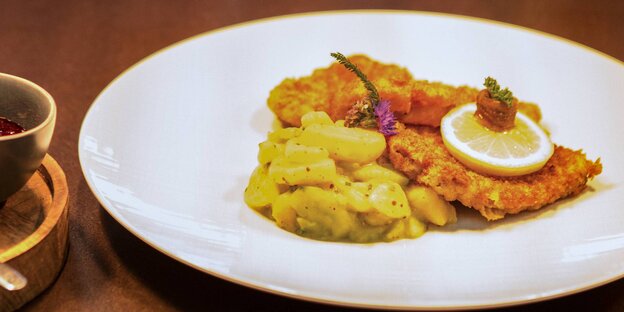 Zwei Wiener Schnitzel mit Kartoffelsalat auf einem weißen Teller Zwei Wiener Schnitzel mit Kartoffelsalat auf einem weißen Teller