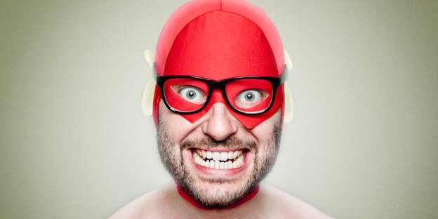 Ein Mann mit roter Superheldenmaske und irrem Grinsen. Ein Mann mit roter Superheldenmaske und irrem Grinsen.