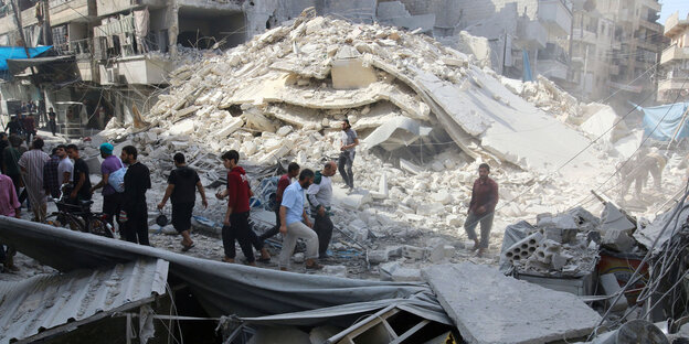 Menschen laufen in den Trümmern von Aleppo Menschen laufen in den Trümmern von Aleppo