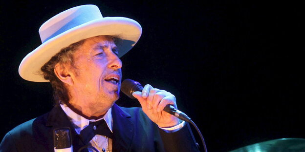 Bob Dylan mit Hut und Mikro auf der Bühne Bob Dylan mit Hut und Mikro auf der Bühne