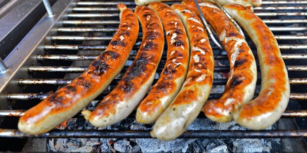 Sechs Bratwürste liegen auf einem Grill Sechs Bratwürste liegen auf einem Grill