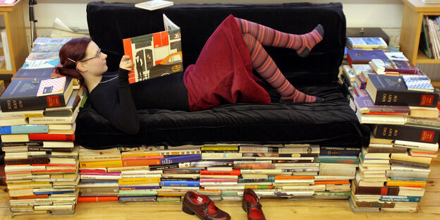 Eine Frau liest auf einer Couch liegend ein Buch Eine Frau liest auf einer Couch liegend ein Buch