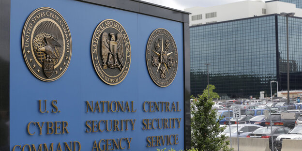 Schild der National Security Agency (NSA), dahinter ein Parkplatz und ein Gebäude Schild der National Security Agency (NSA), dahinter ein Parkplatz und ein Gebäude