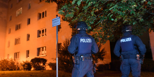 Polizisten stehen vor einem Wohnhaus Polizisten stehen vor einem Wohnhaus
