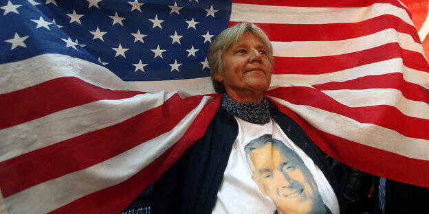 Eine Frau trägt ein T-Shirt mit dem Gesicht Djucanovics und hält eine US-Fahne in die Höhe, die über ihre Schultern fällt Eine Frau trägt ein T-Shirt mit dem Gesicht Djucanovics und hält eine US-Fahne in die Höhe, die über ihre Schultern fällt